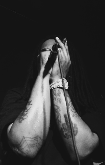 Halloween Riot — hands raised on the mic, tattoos showing